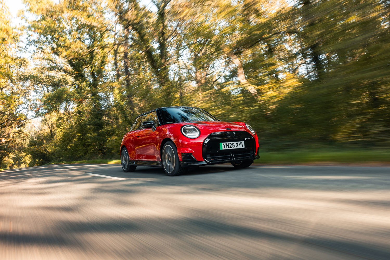 Three MINI models racing. A MINI Cooper, Countryman and Convertible captured from the side, speeding down an open road.